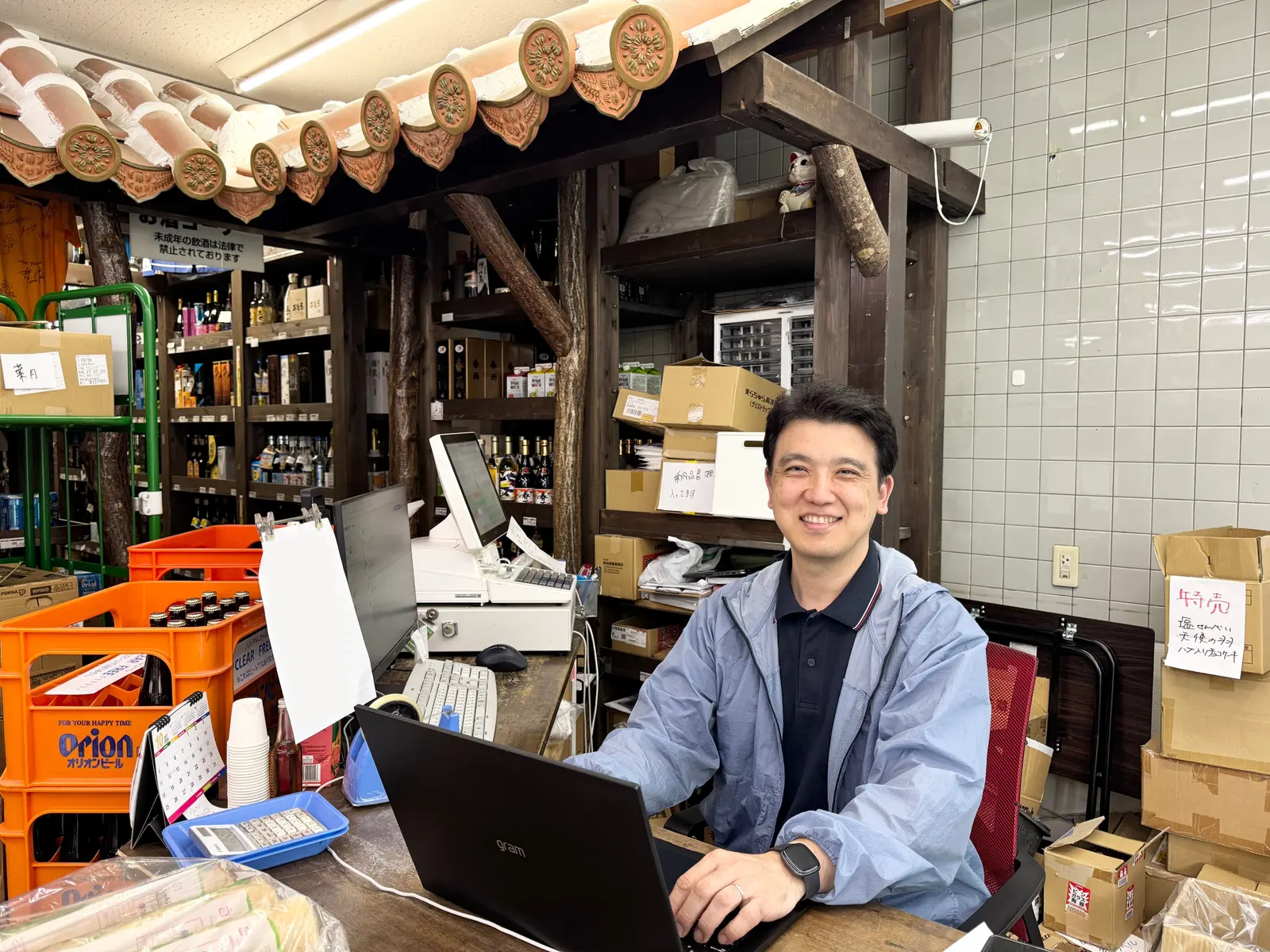 倉庫の一角にある事務所。デスクで作業する代表の島袋